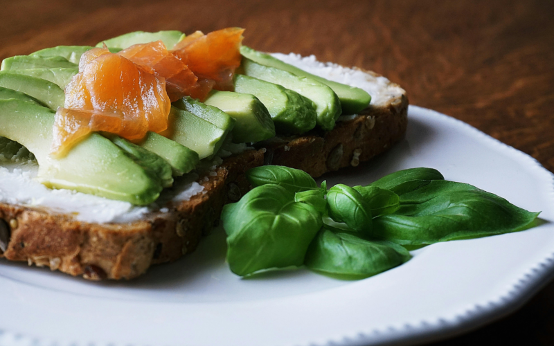 A plate of grilled salmon, quinoa, avocado, spinach and tomatoes representing a heart-healthy Mediterranean-style meal.